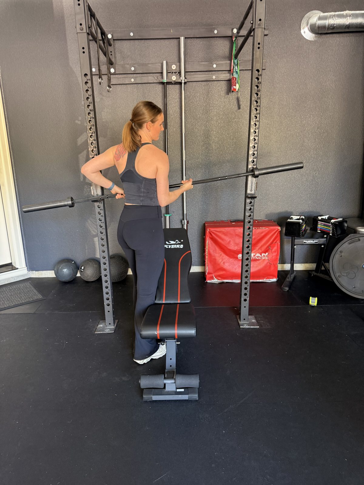 Coach Julia setting up a barbell at the rack in the Burnt Bridge studio