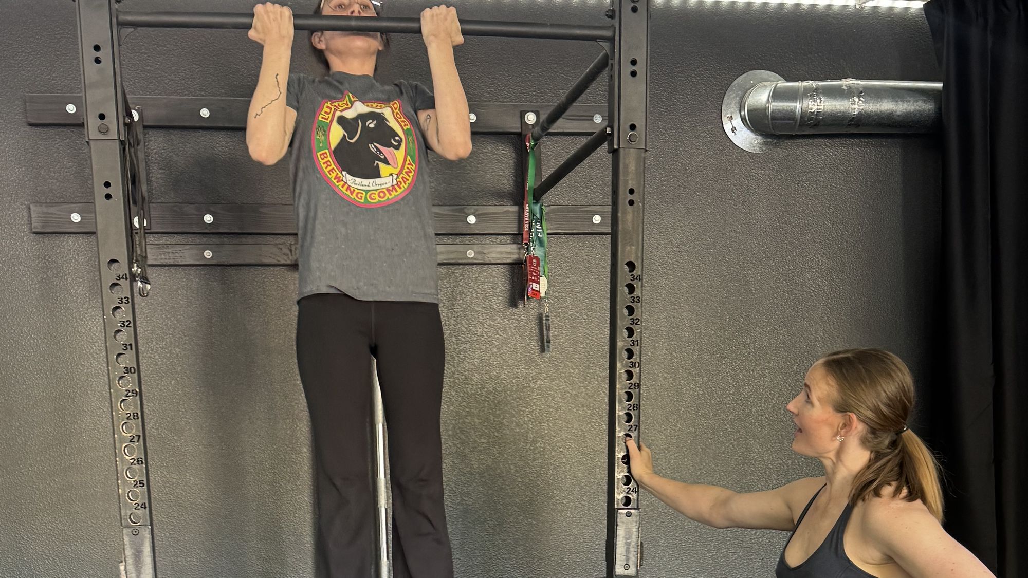 Coach Julia spotting a client through band-assisted pull-ups